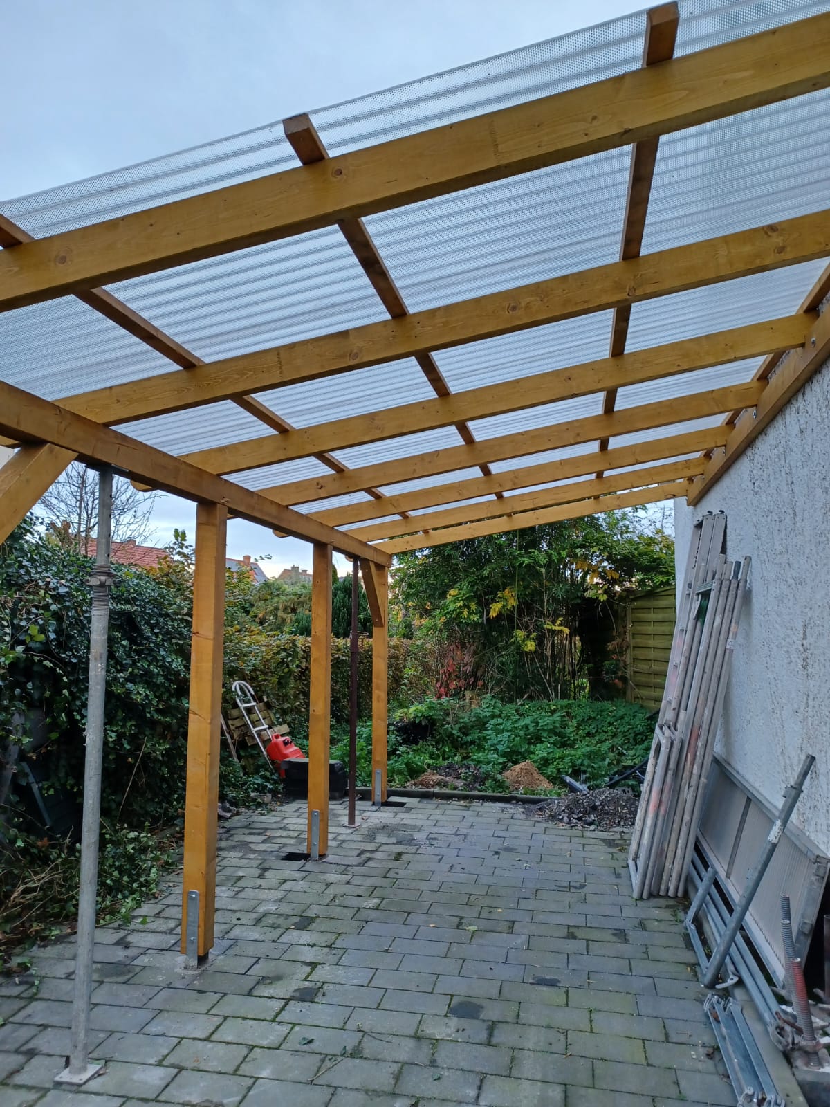 Fertiggestellte Terrassenüberdachung aus Holz mit lichtdurchlässiger Dacheindeckung
